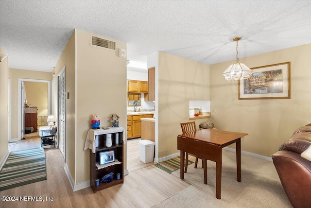 interior space featuring baseboards, visible vents, light wood-style flooring, and a textured ceiling