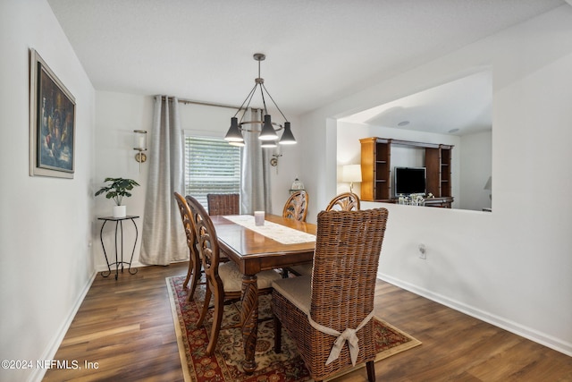 dining space featuring an inviting chandelier, wood finished floors, and baseboards