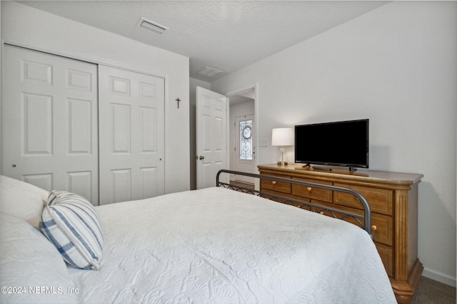 bedroom featuring a closet, visible vents, a textured ceiling, and baseboards