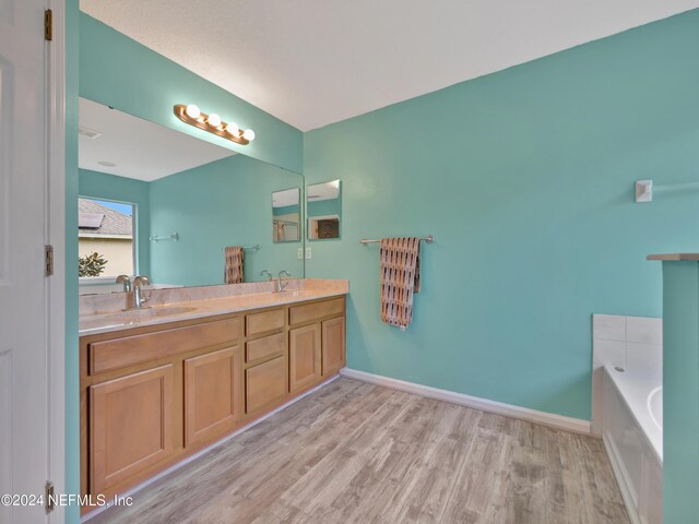 bathroom with a washtub, hardwood / wood-style floors, and vanity