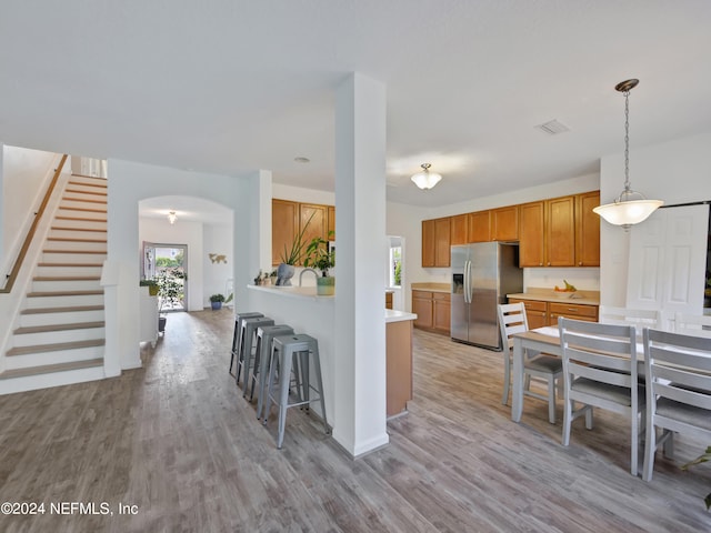 kitchen featuring light hardwood / wood-style floors, stainless steel fridge, and hanging light fixtures