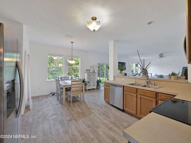 kitchen featuring stainless steel appliances, light hardwood / wood-style flooring, sink, a textured ceiling, and pendant lighting