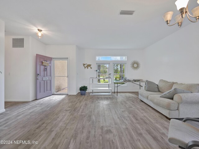 unfurnished living room featuring a notable chandelier and wood-type flooring