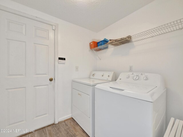 laundry area featuring washing machine and clothes dryer and light hardwood / wood-style flooring