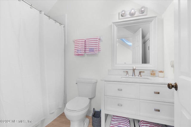 bathroom with toilet, vanity, curtained shower, lofted ceiling, and hardwood / wood-style flooring