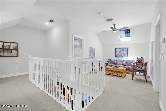 hallway featuring vaulted ceiling with skylight and light colored carpet