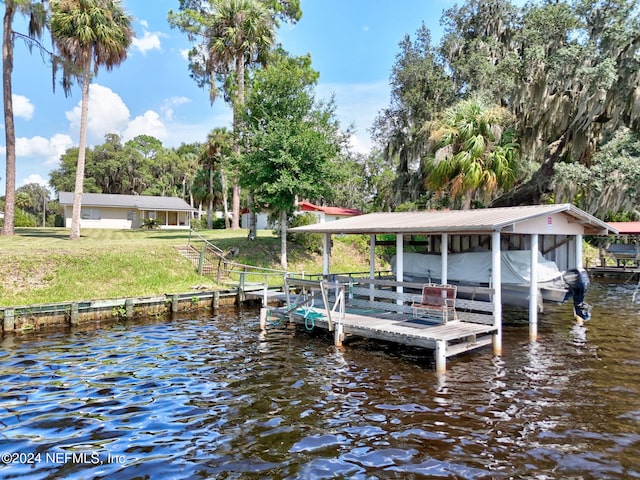 view of dock with a yard and a water view