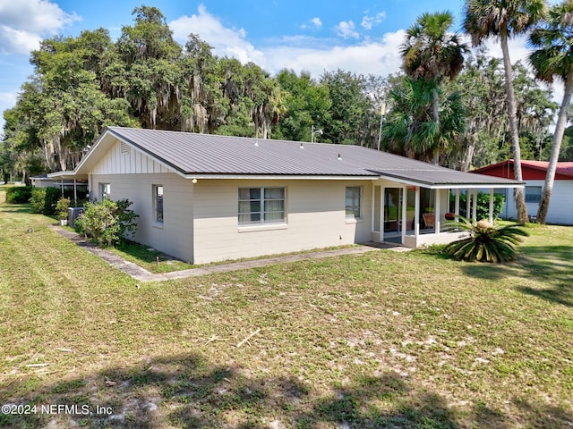 back of house featuring metal roof, a patio area, and a yard