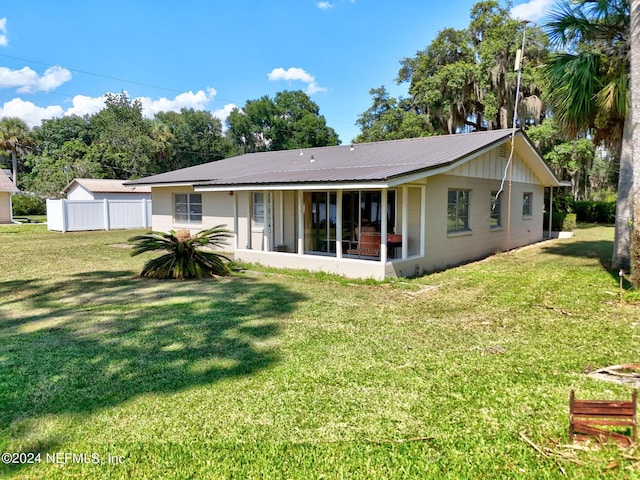 back of property featuring a sunroom, metal roof, a yard, and fence