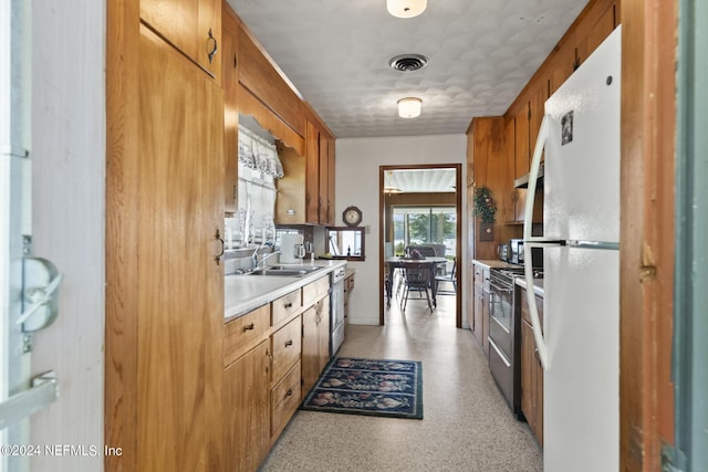 kitchen featuring brown cabinets, freestanding refrigerator, light countertops, and electric range