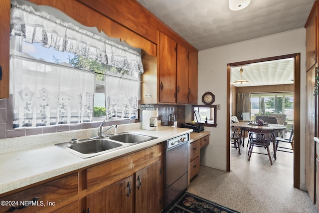 kitchen featuring a sink, light countertops, brown cabinets, decorative backsplash, and dishwasher