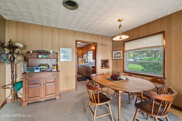 carpeted dining room featuring wood walls