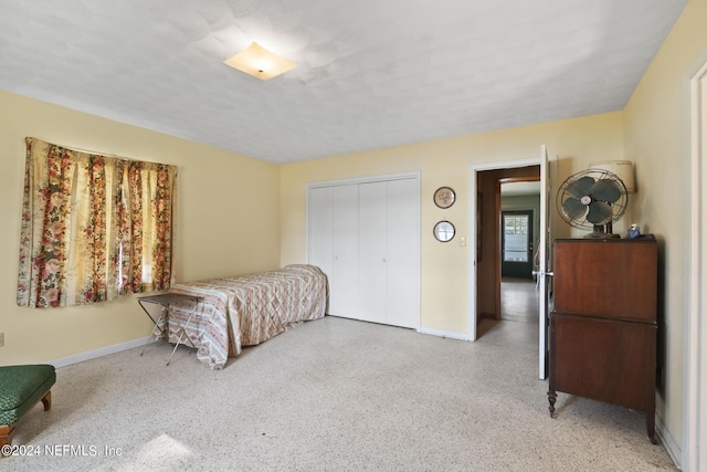 bedroom with light speckled floor, a closet, a textured ceiling, and baseboards