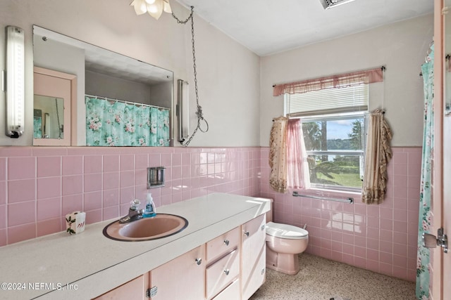 bathroom with toilet, decorative backsplash, vanity, and tile walls