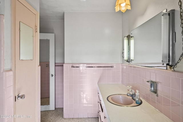 bathroom featuring a wainscoted wall, speckled floor, vanity, and tile walls