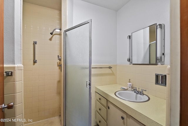 bathroom with a stall shower, wainscoting, vanity, and tile walls