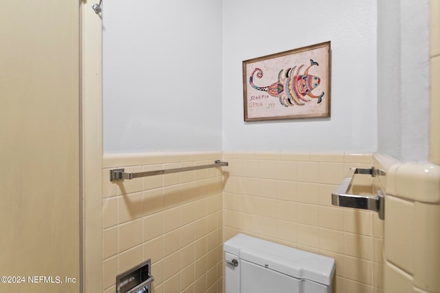 bathroom featuring tile walls and toilet