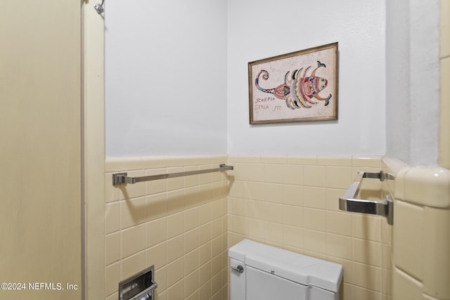 bathroom with wainscoting, toilet, and tile walls