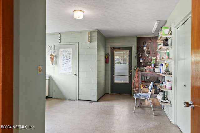 entrance foyer featuring a textured ceiling, light floors, and concrete block wall