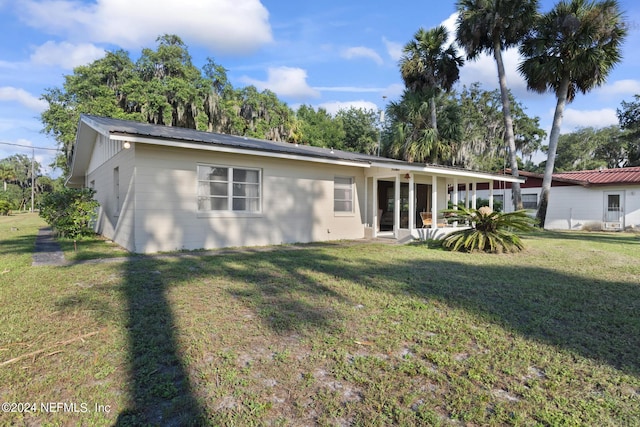 back of house with metal roof and a yard