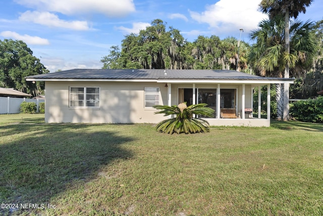 rear view of property with metal roof, a lawn, and concrete block siding