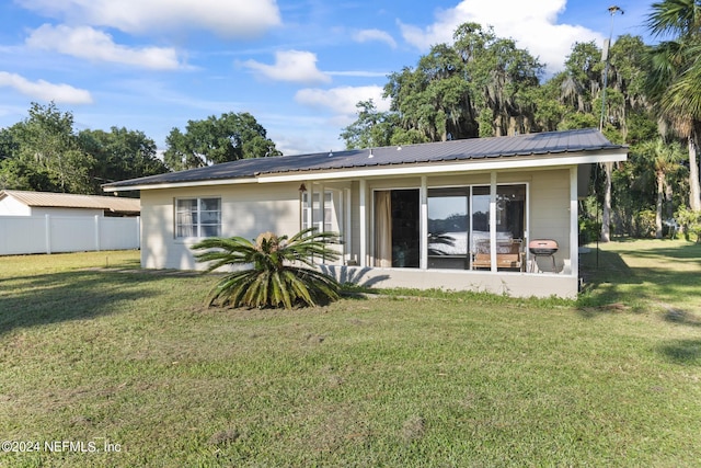 rear view of house with fence, metal roof, and a lawn