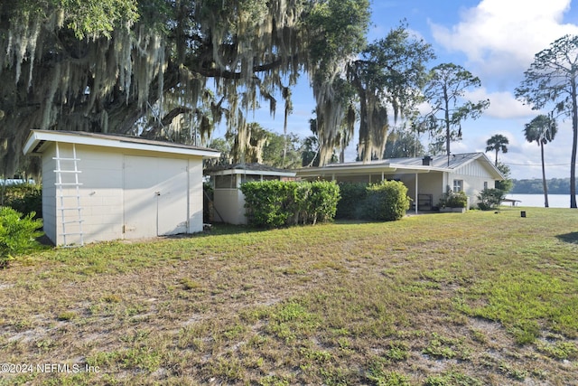 view of yard featuring a water view, an outdoor structure, and a storage shed