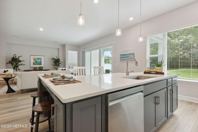 kitchen featuring sink, dishwasher, a kitchen island with sink, and light wood-type flooring