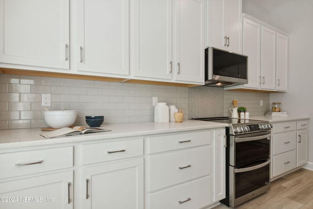 kitchen with backsplash, appliances with stainless steel finishes, light hardwood / wood-style floors, light stone counters, and white cabinets