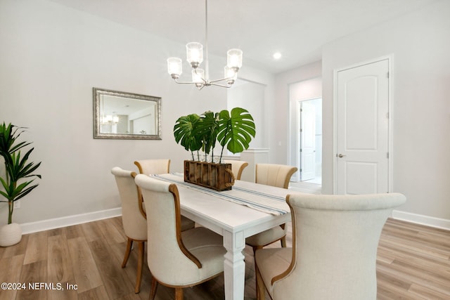 dining space with light wood-type flooring and a notable chandelier