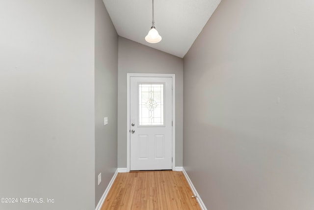 doorway to outside featuring light wood-type flooring and vaulted ceiling