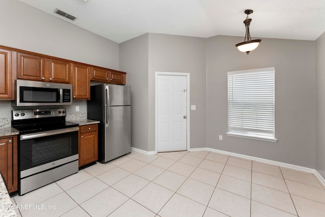 kitchen featuring light tile patterned floors, decorative light fixtures, light stone counters, stainless steel appliances, and lofted ceiling