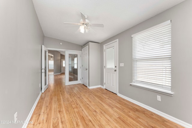 interior space with light wood-type flooring, ceiling fan, lofted ceiling, and french doors