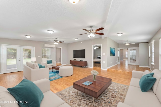 living room featuring a wall mounted AC, a textured ceiling, ceiling fan, french doors, and hardwood / wood-style flooring