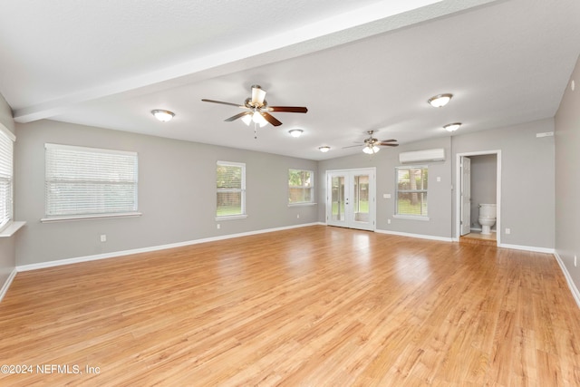 unfurnished living room with a wall unit AC, light hardwood / wood-style flooring, ceiling fan, french doors, and beam ceiling