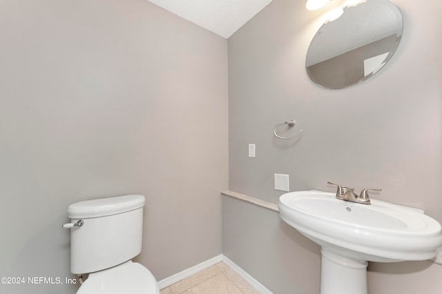 bathroom with toilet, sink, and tile patterned floors