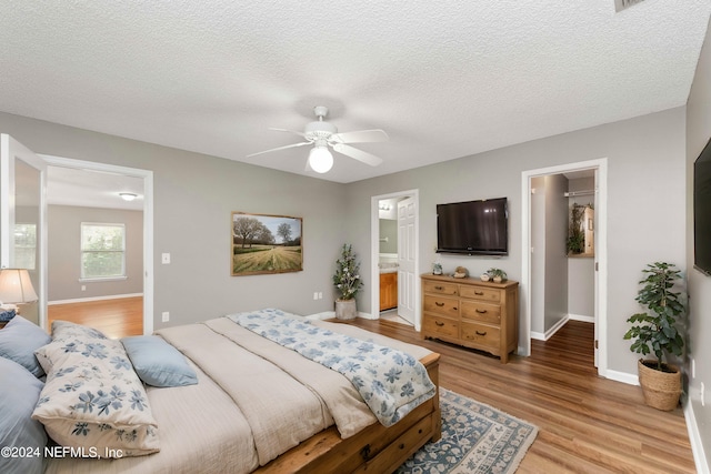 bedroom featuring light wood-type flooring, ceiling fan, connected bathroom, and a textured ceiling