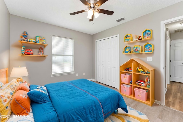 bedroom featuring light hardwood / wood-style floors, a textured ceiling, ceiling fan, and a closet