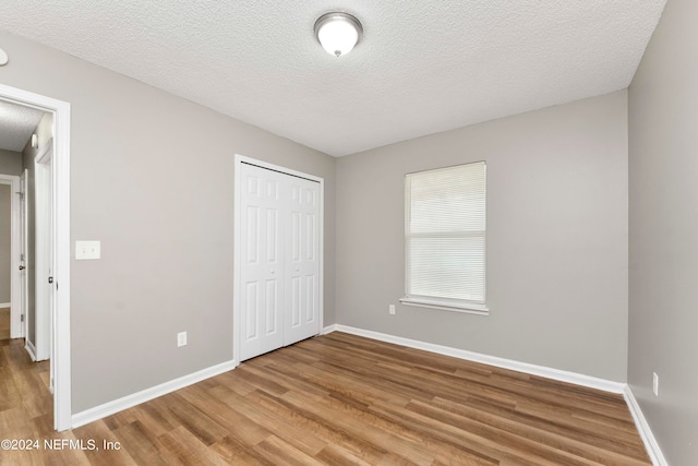 unfurnished bedroom with a textured ceiling, hardwood / wood-style flooring, and a closet