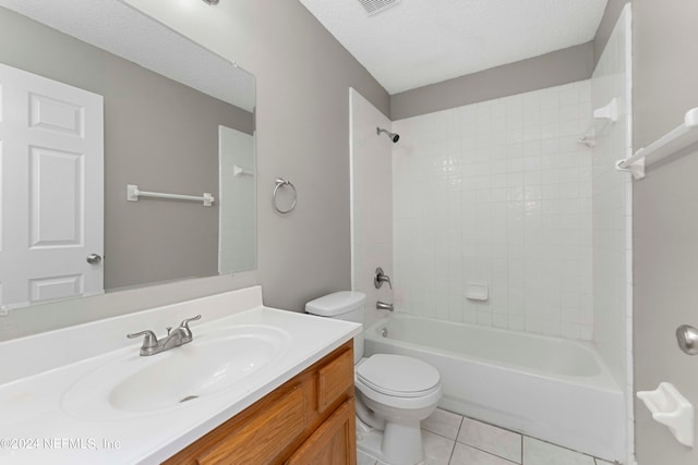 full bathroom featuring tile patterned flooring, toilet, tiled shower / bath combo, vanity, and a textured ceiling