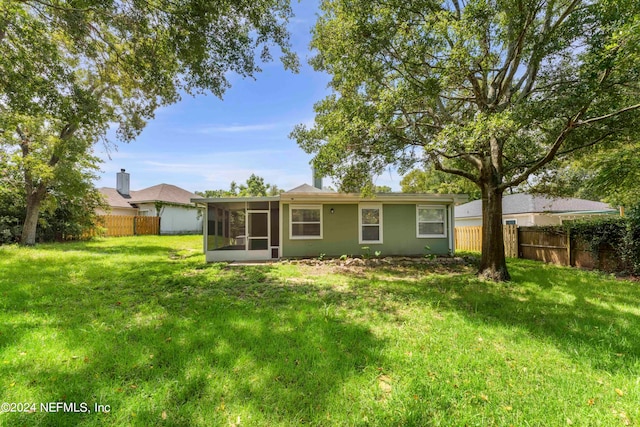 rear view of property with a yard and a sunroom