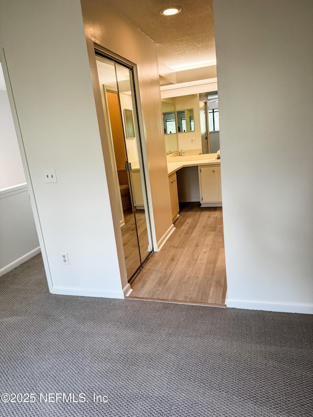 hall with light carpet and a textured ceiling