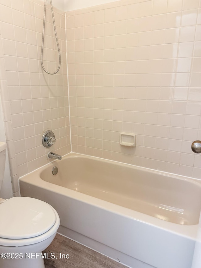 bathroom with toilet, tiled shower / bath, and hardwood / wood-style floors