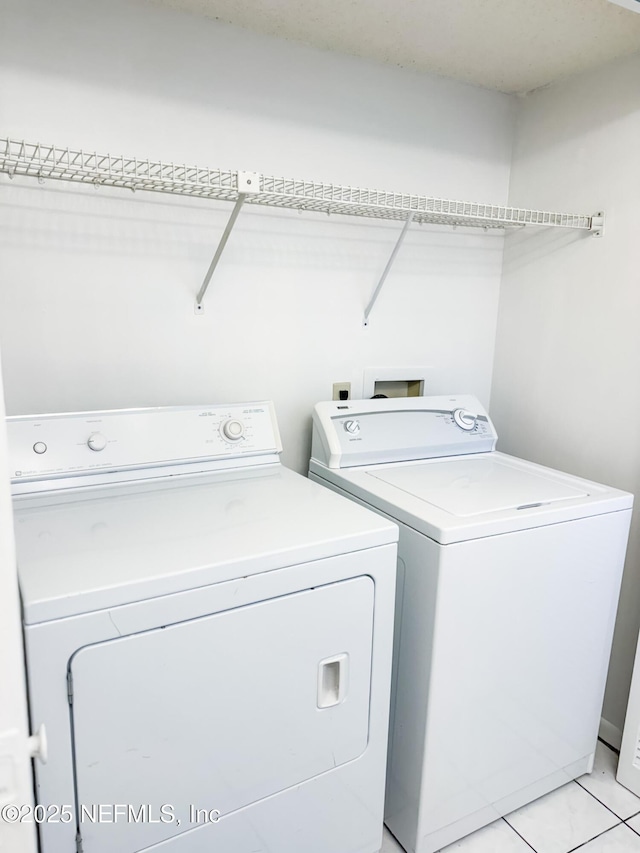 laundry room with light tile patterned flooring and washing machine and clothes dryer