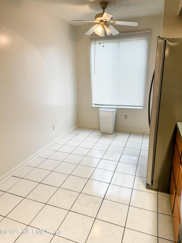 spare room featuring a textured ceiling, ceiling fan, and light tile patterned floors