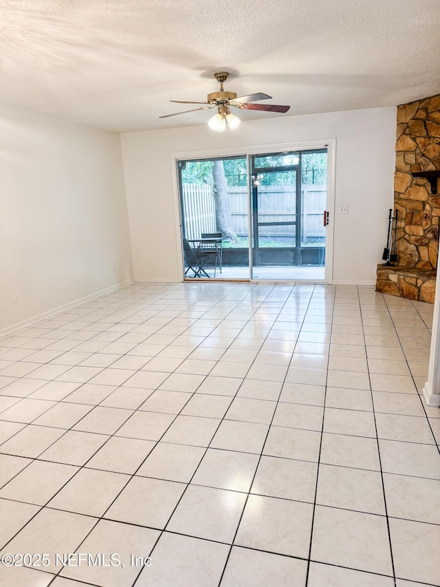 tiled spare room featuring ceiling fan, a textured ceiling, and a healthy amount of sunlight