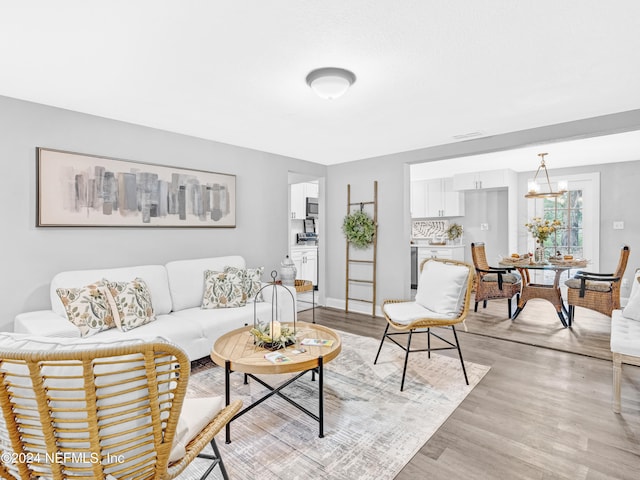 living room with light hardwood / wood-style floors and a notable chandelier