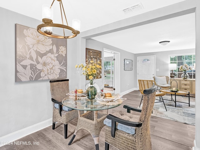 dining space with visible vents, a notable chandelier, baseboards, and wood finished floors