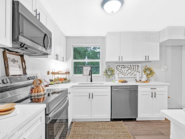 kitchen with white cabinetry, appliances with stainless steel finishes, sink, and light wood-type flooring