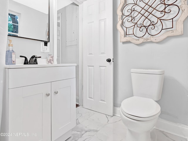 half bath featuring toilet, marble finish floor, baseboards, and vanity